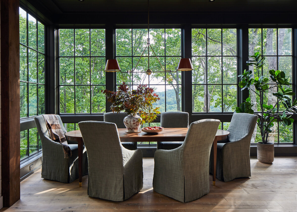 dark wood dining room with wall of windows over looking trees