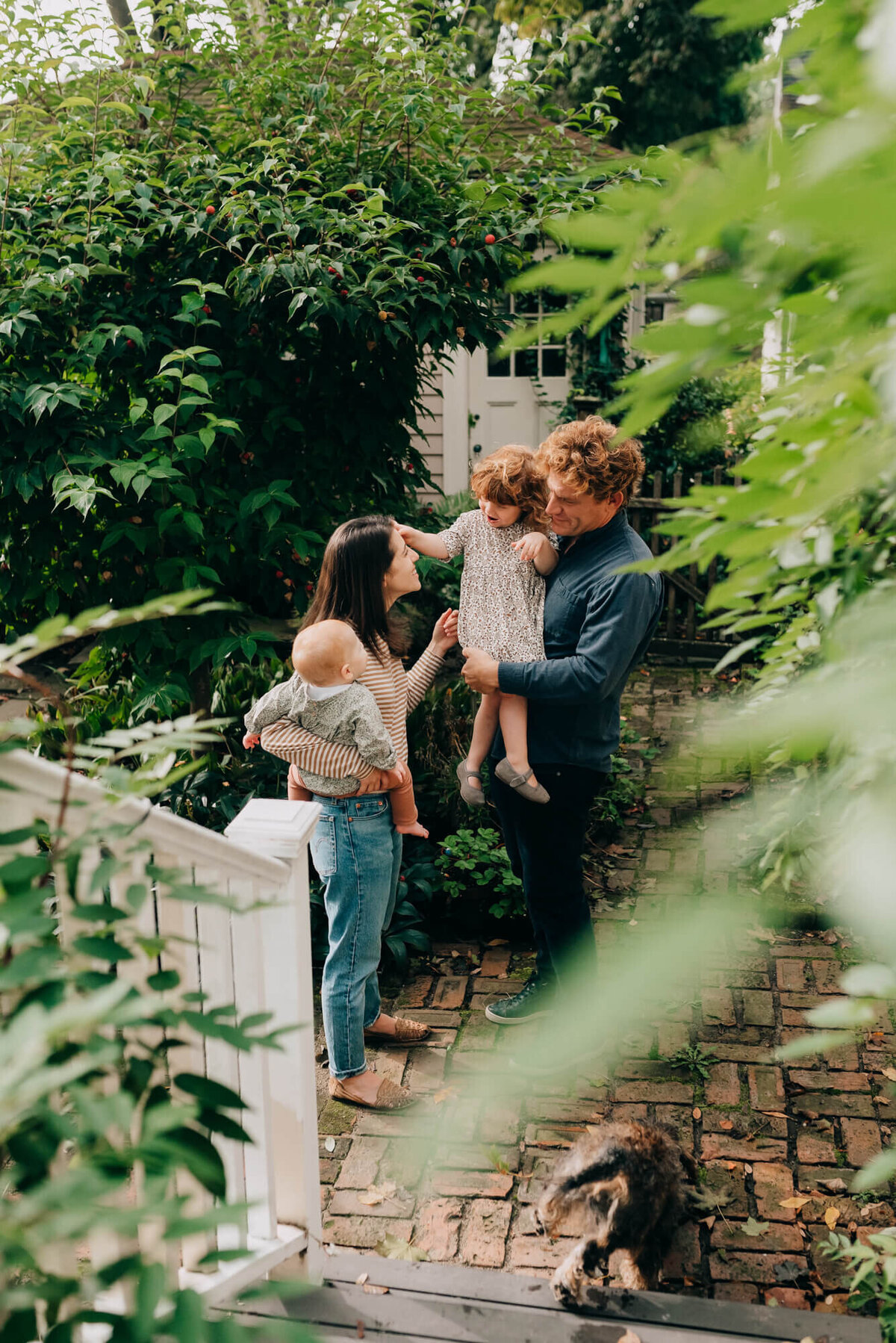 A family stand together on their back deck, the mother is holding their youngest daughter and the father is holding the oldest daughter