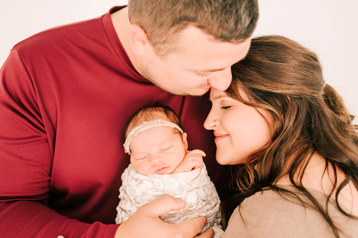 Springfield Mo newborn photographer captures parents hugging holding newborn baby girl