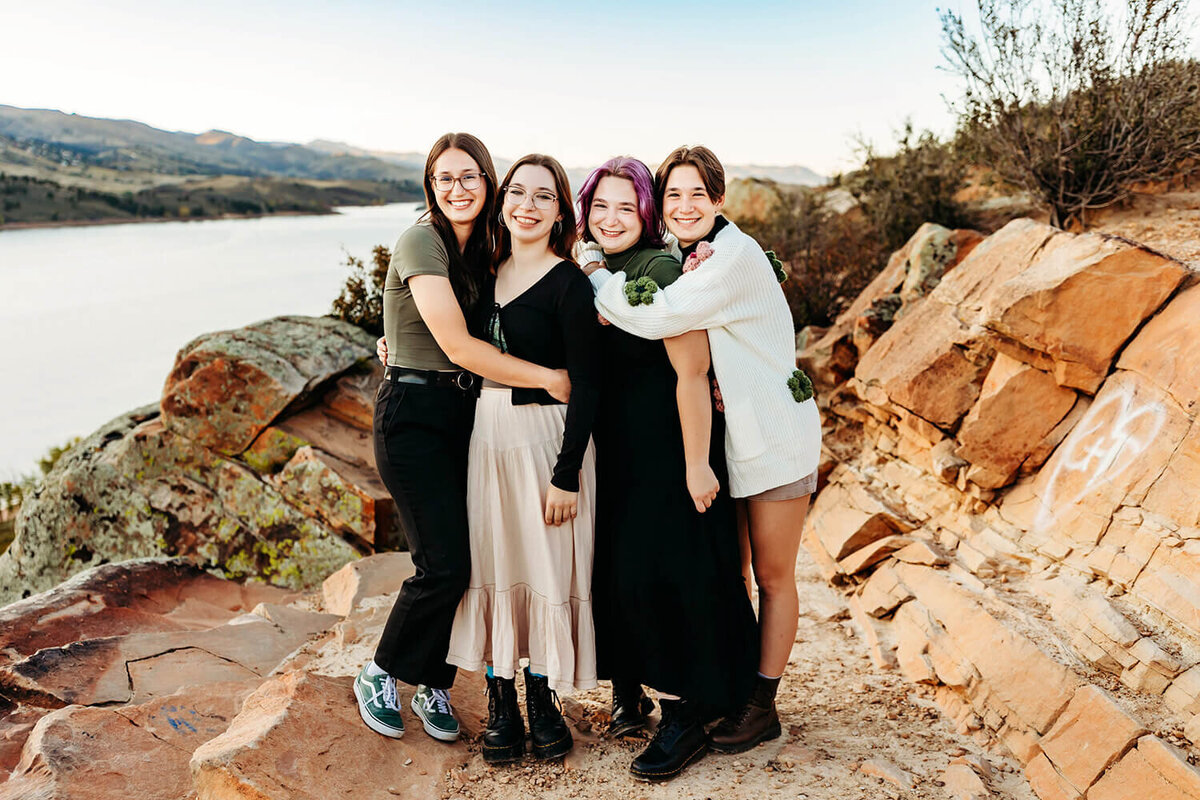 Four teenage sisters hugging and smiling together at Horsetooth Reservoir in Fort Collins.