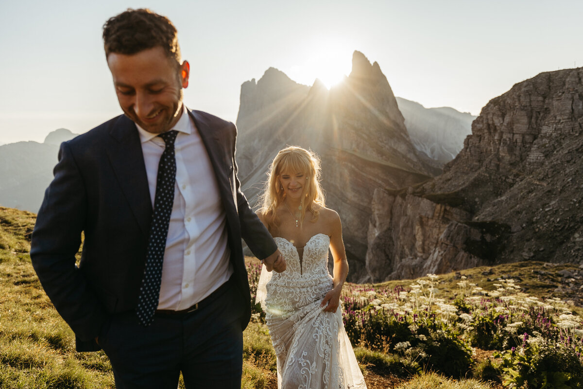 Bride and groom walking through mountain meadow golden hour