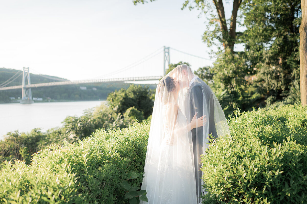 couple shares romantic kiss under veil during sunset portraits at grandview