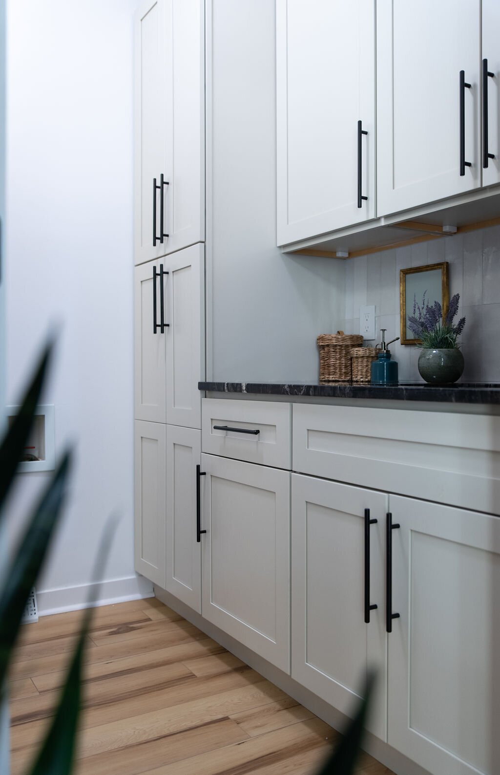 off-white cabinets with black handles in a laundry room