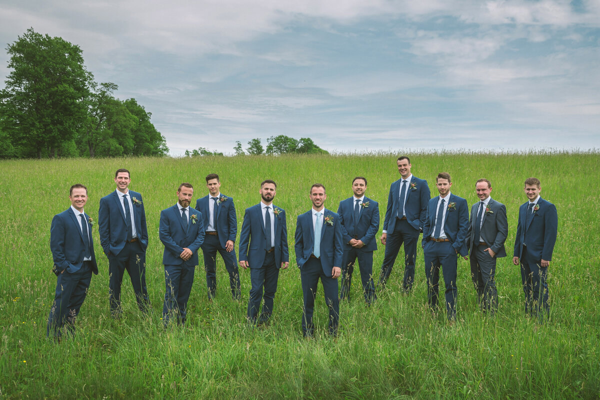 Groomsmen posing for photography in a field.