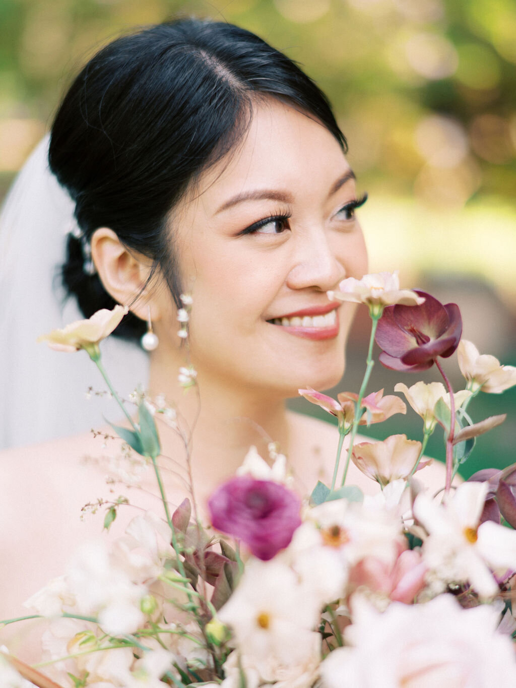 beautiful bride holding her bouquet of hellebore, ranunculus, lisianthus, butterfly ranunculus in shades of dusty rose and white