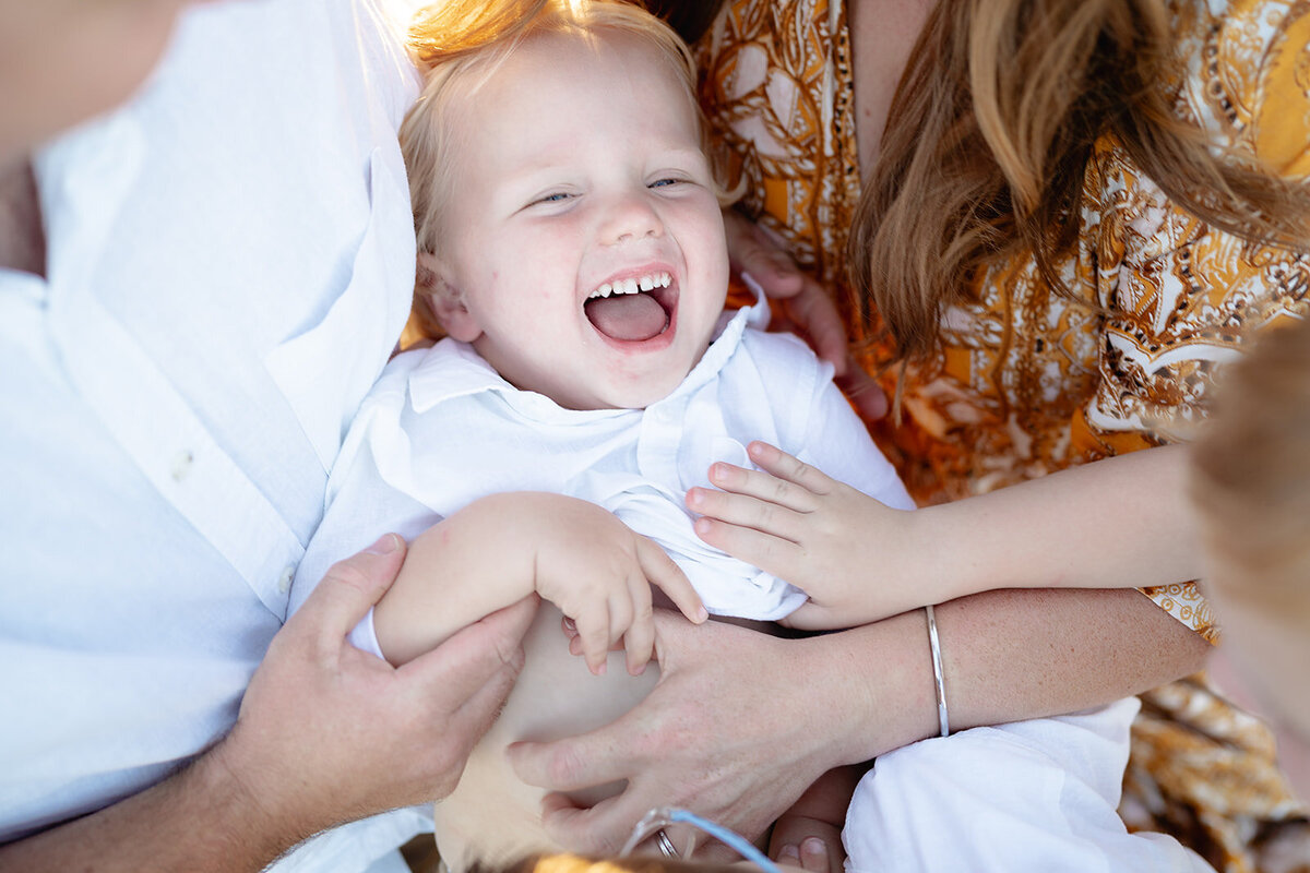 Close-up of a joyful toddler laughing while being cuddled during a playful family photography session in Geelong.