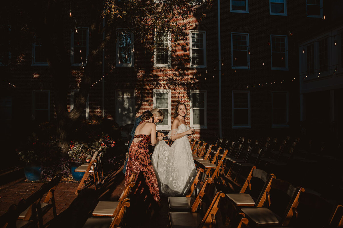 A person holding up the back of someone's wedding dress 