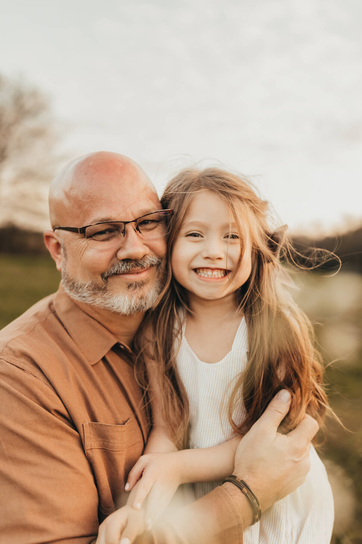 dad holds in his baby girl while she smiles and giggles with him.