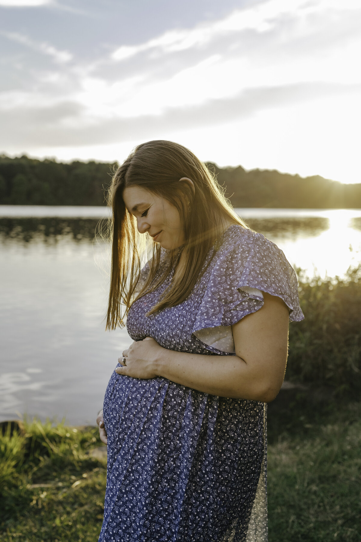 Verona B Photography captures a stunning maternity picture of a mom holding her belly at Silver Creek metro Park in Norton, OH. You could see the mom’s love on her face for her unborn baby while the sun was setting in this beautiful lake setting near Akron, OH.
