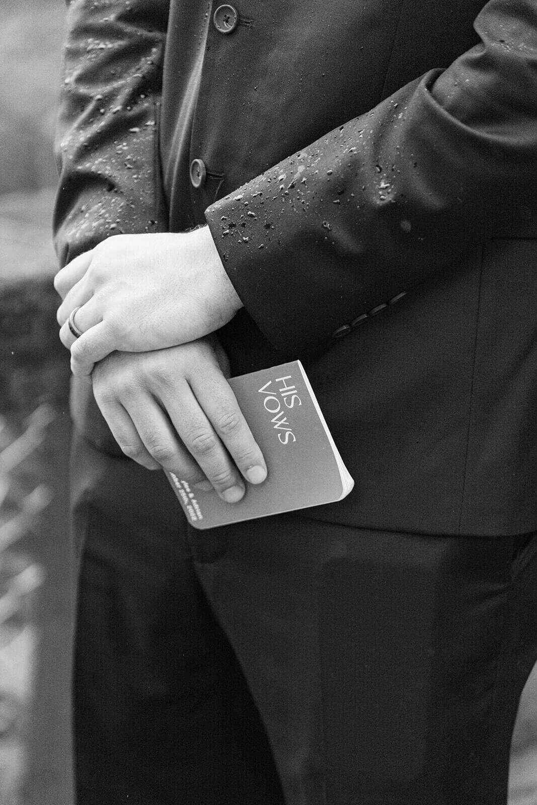 close up of groom holding vow book