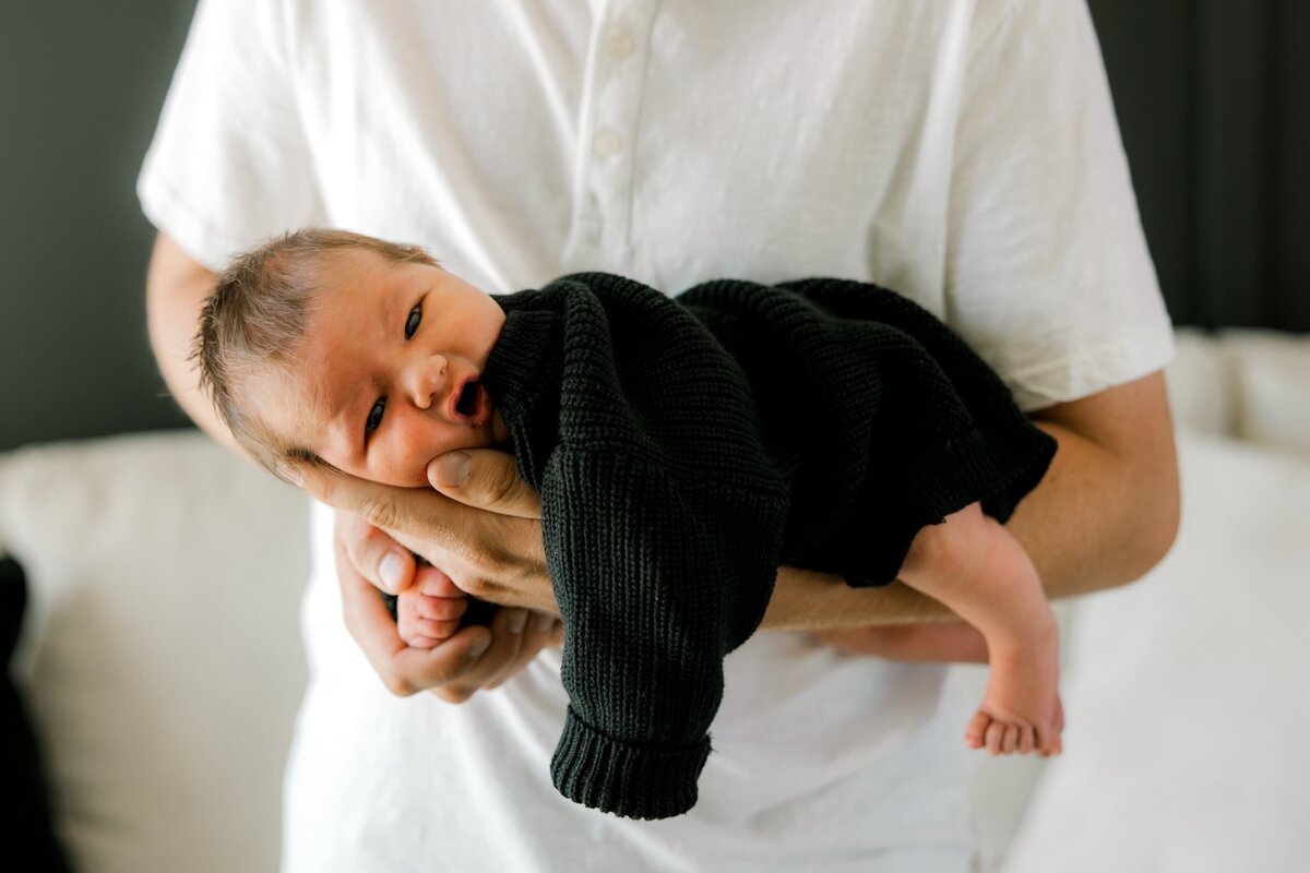 newborn laying on dad's forearm.