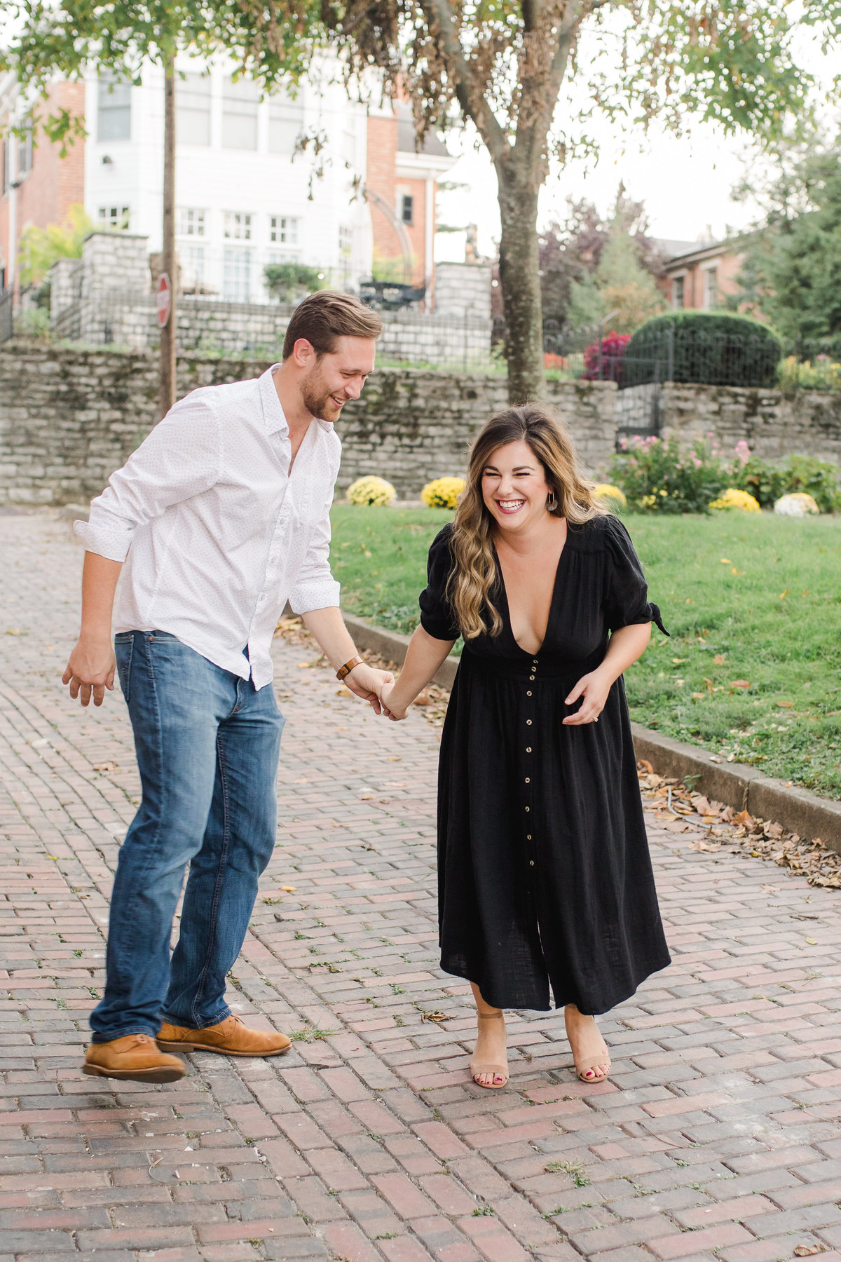 A couple faces each other in candid laughter during their engagement session in Covington, KY