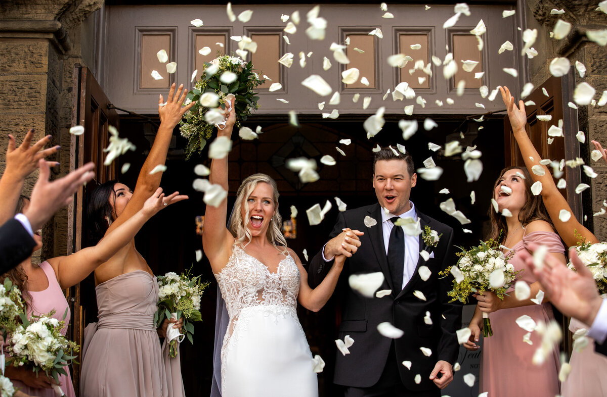Flower petals fall on the bridal couple as they leave their Catholic church.