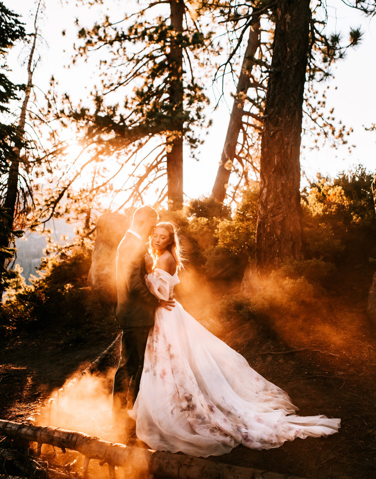 Couples Photography, Man in a blue suit holds woman in a wedding dress in the golden sun as dust clouds are kicked up all around them.