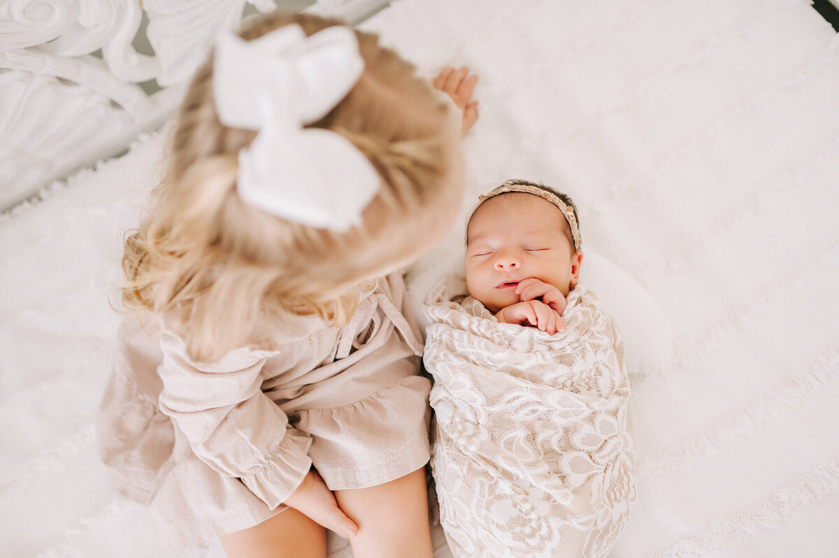 newborn picture in Branson of toddler sister sitting by sleeping newborn sister