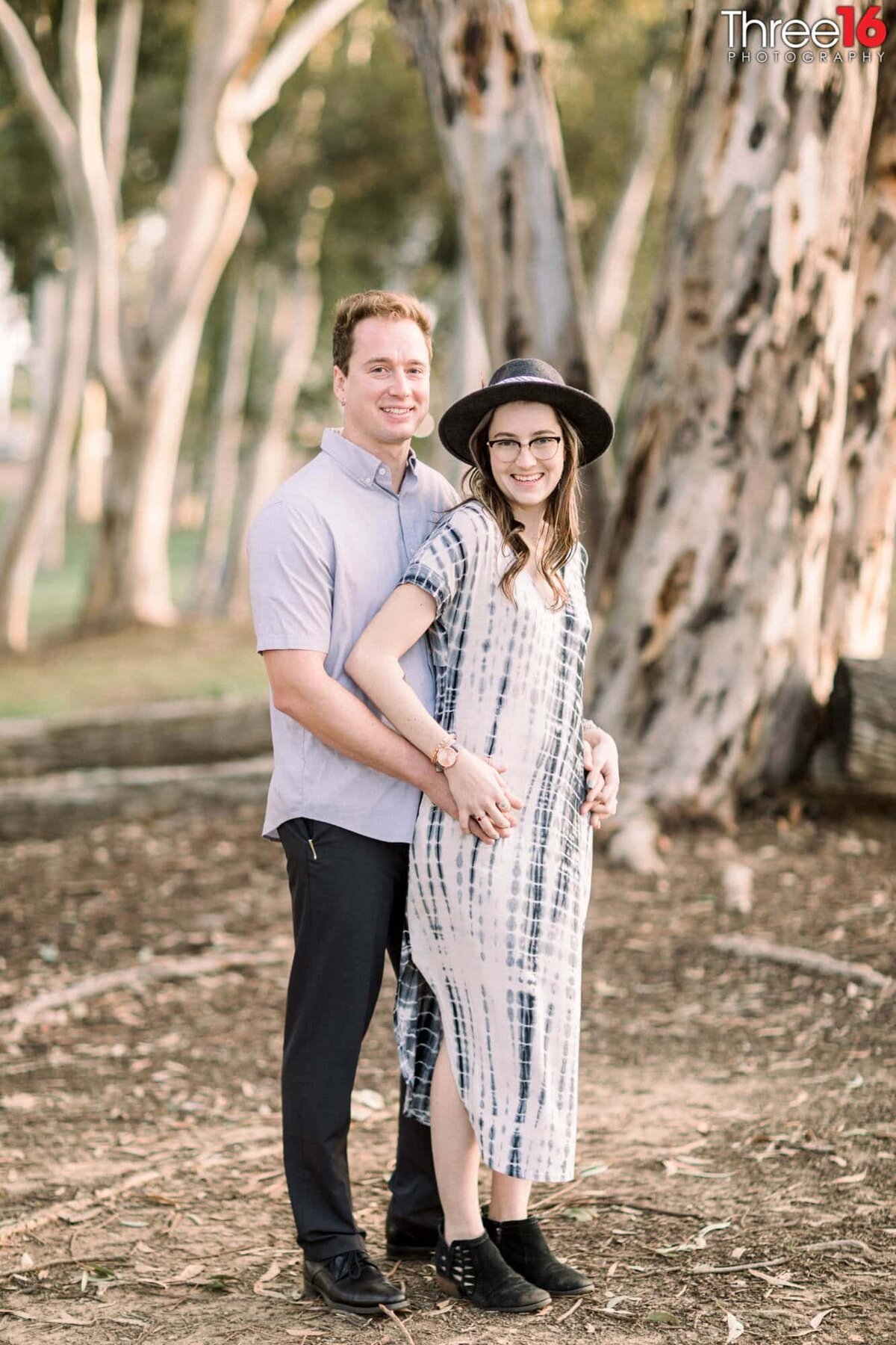 Groom to be holds his Bride from behind as they smile for engagement photos