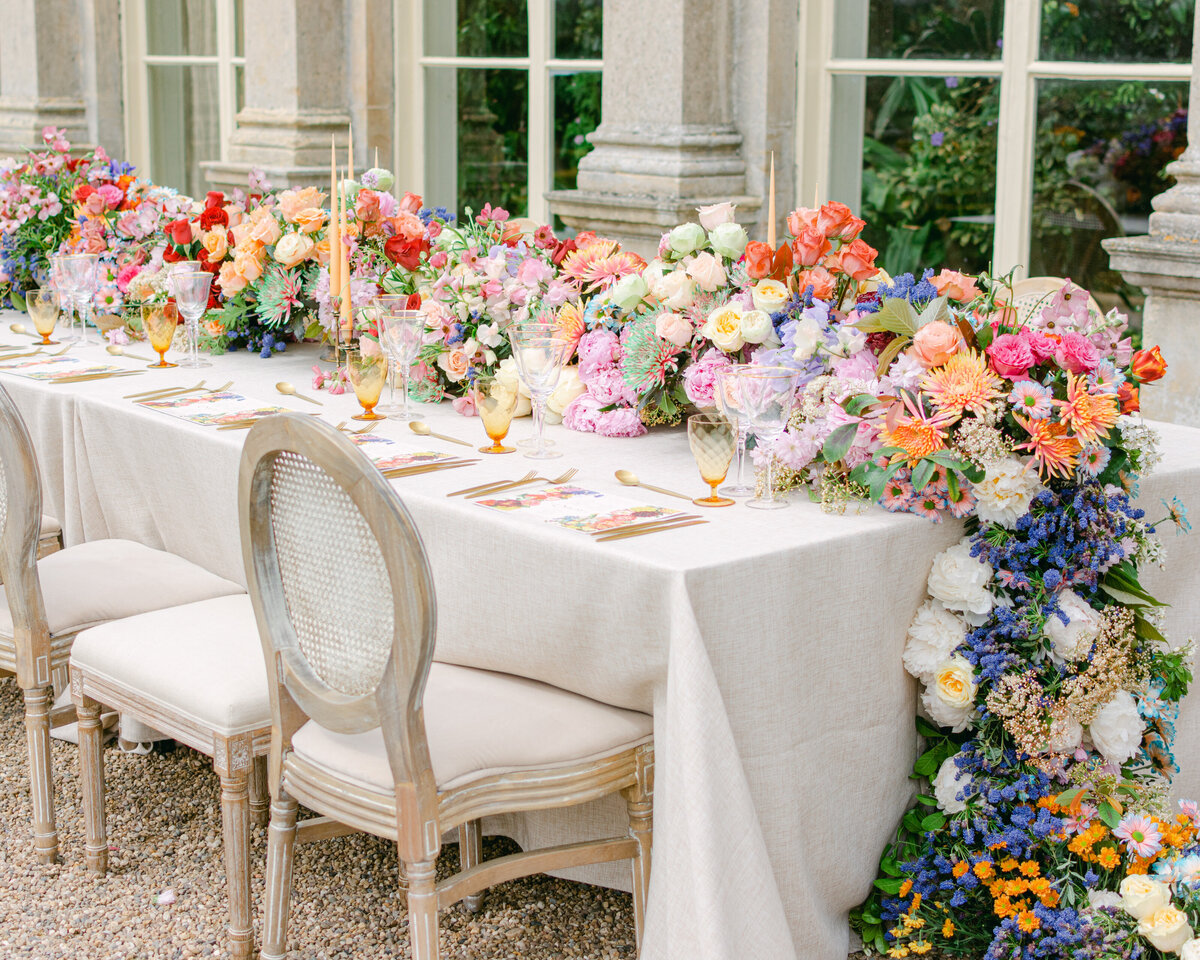 Stunning outdoor wedding breakfast with river of bright flowers