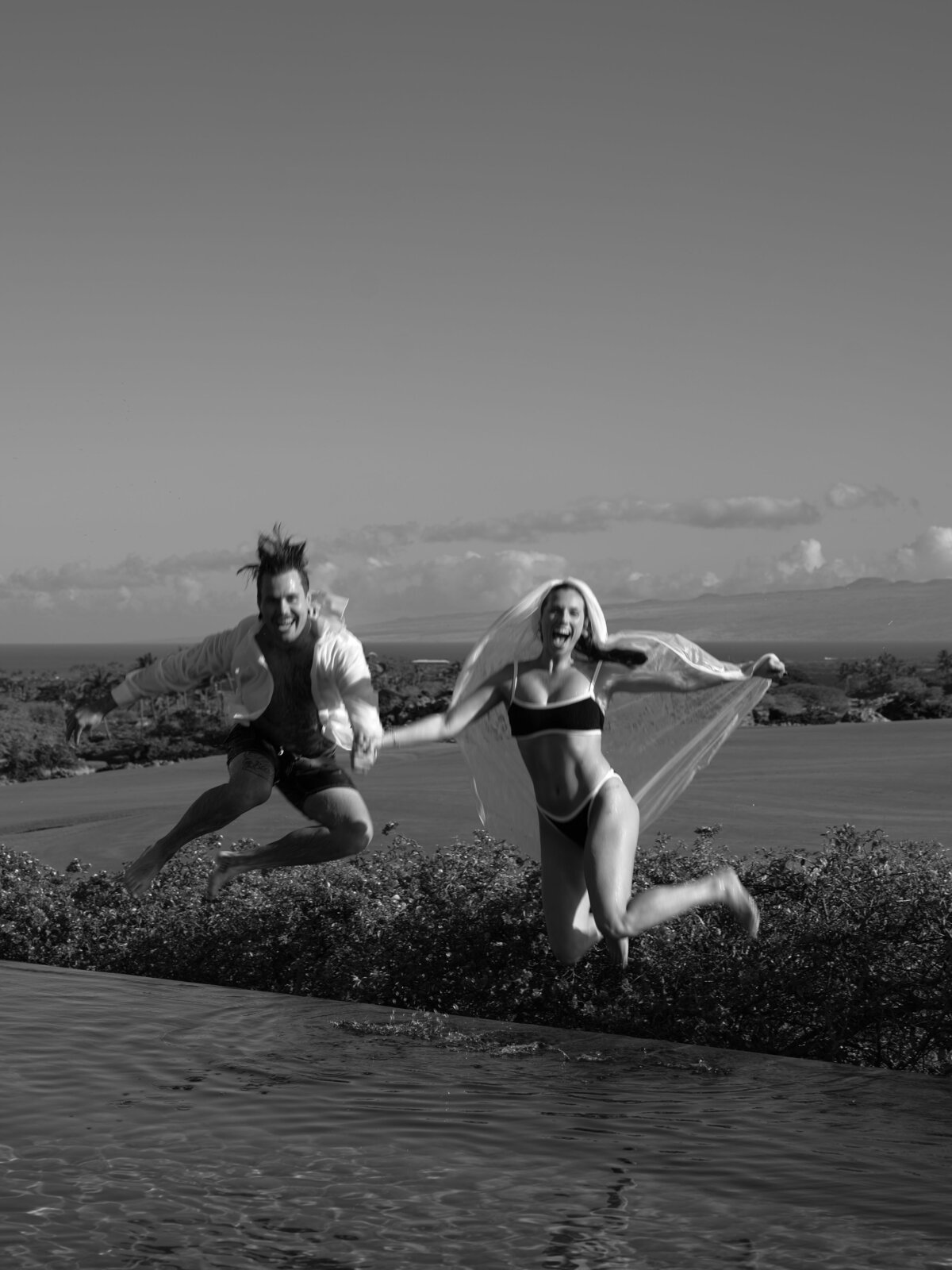 couple jumping into pool after getting married