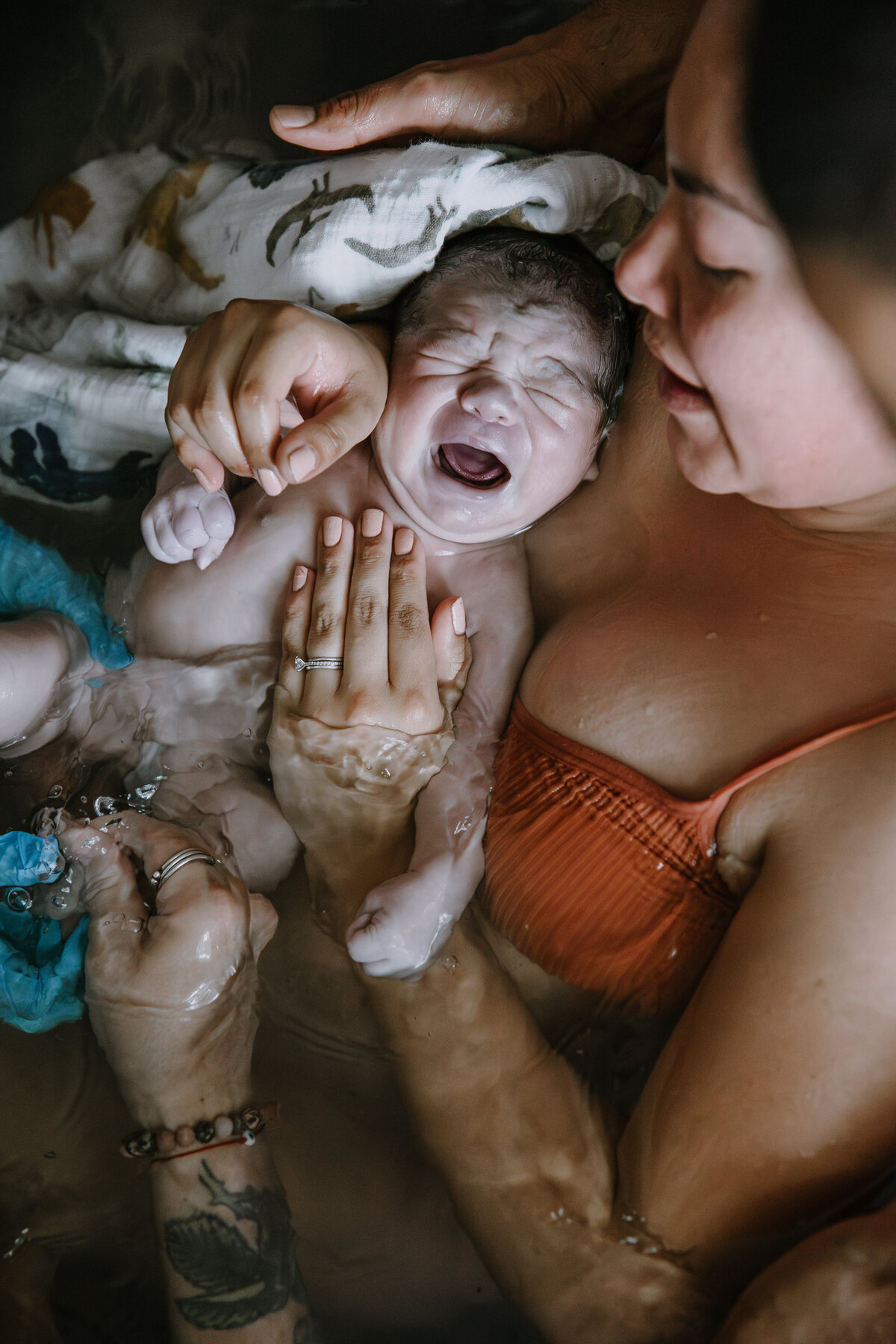 Mother holds crying newborn after home birth in tub