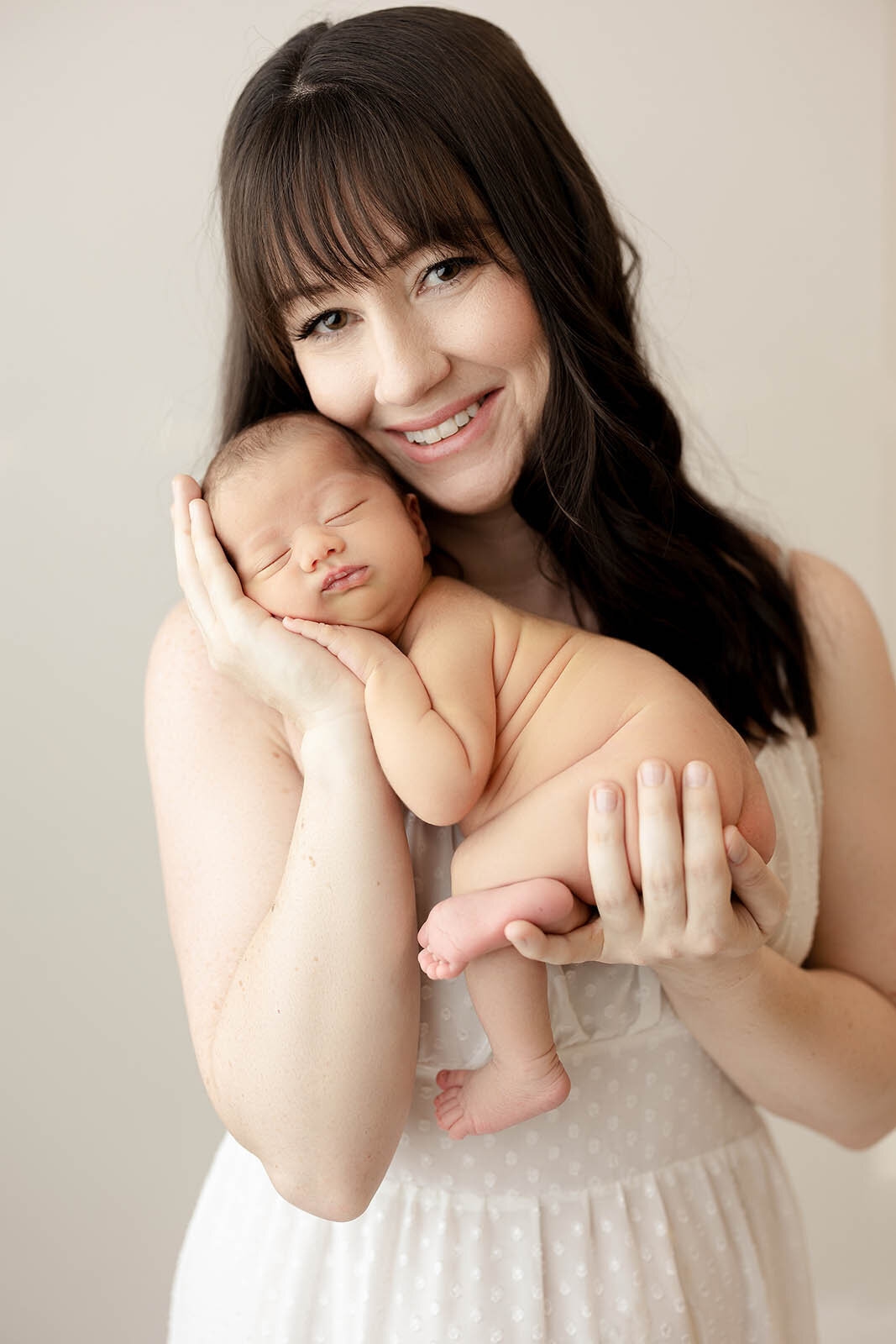 A baby is posed in their moms hands by a surrey newborn photographer