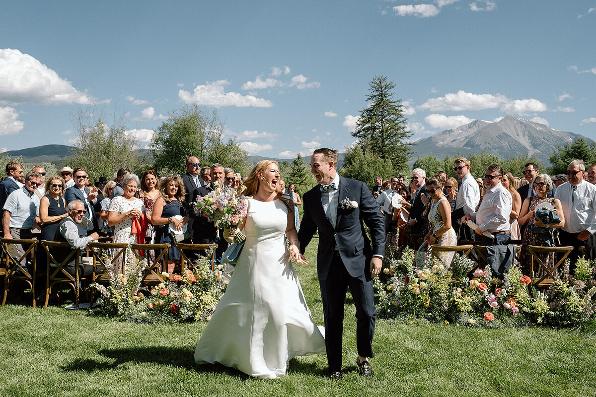 bride and groom celebrate as they walk down the aisle in Colorado