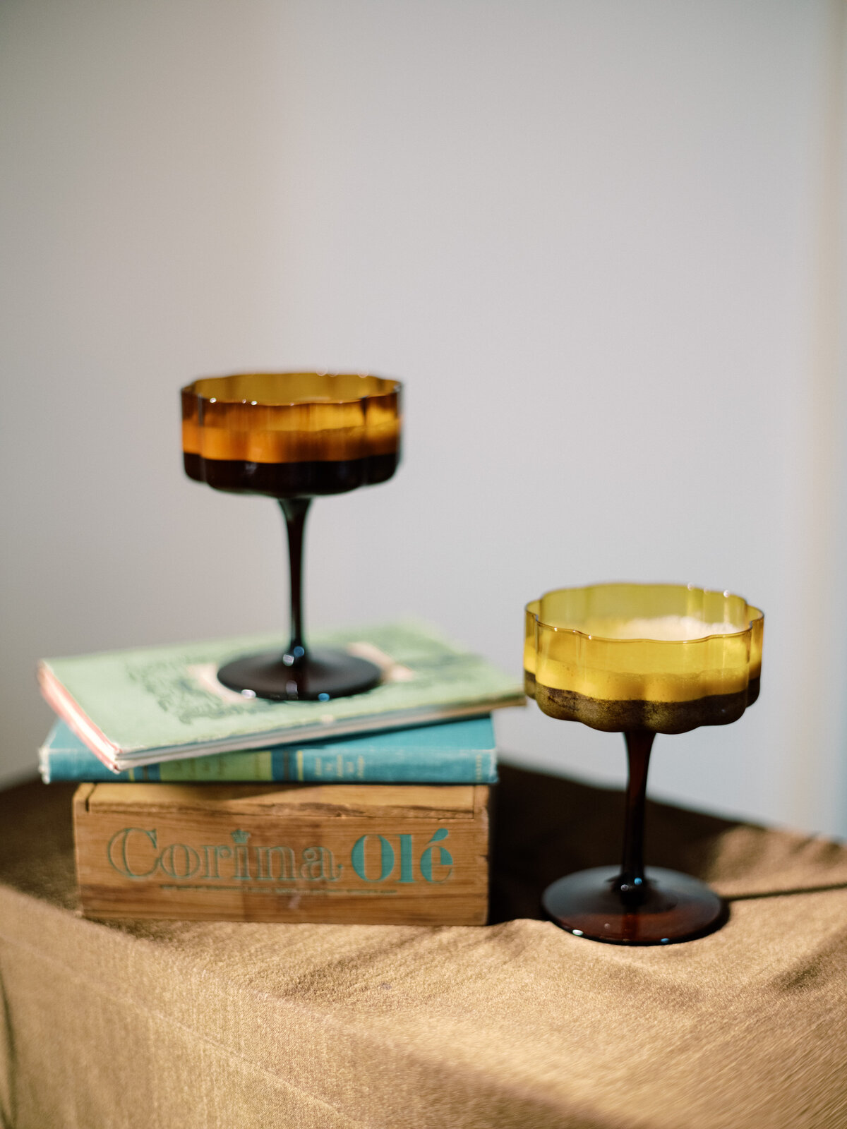Charming vintage glassware displayed atop rustic books creating a warm, inviting atmosphere, ideal for stylish gatherings and cozy moments with friends.