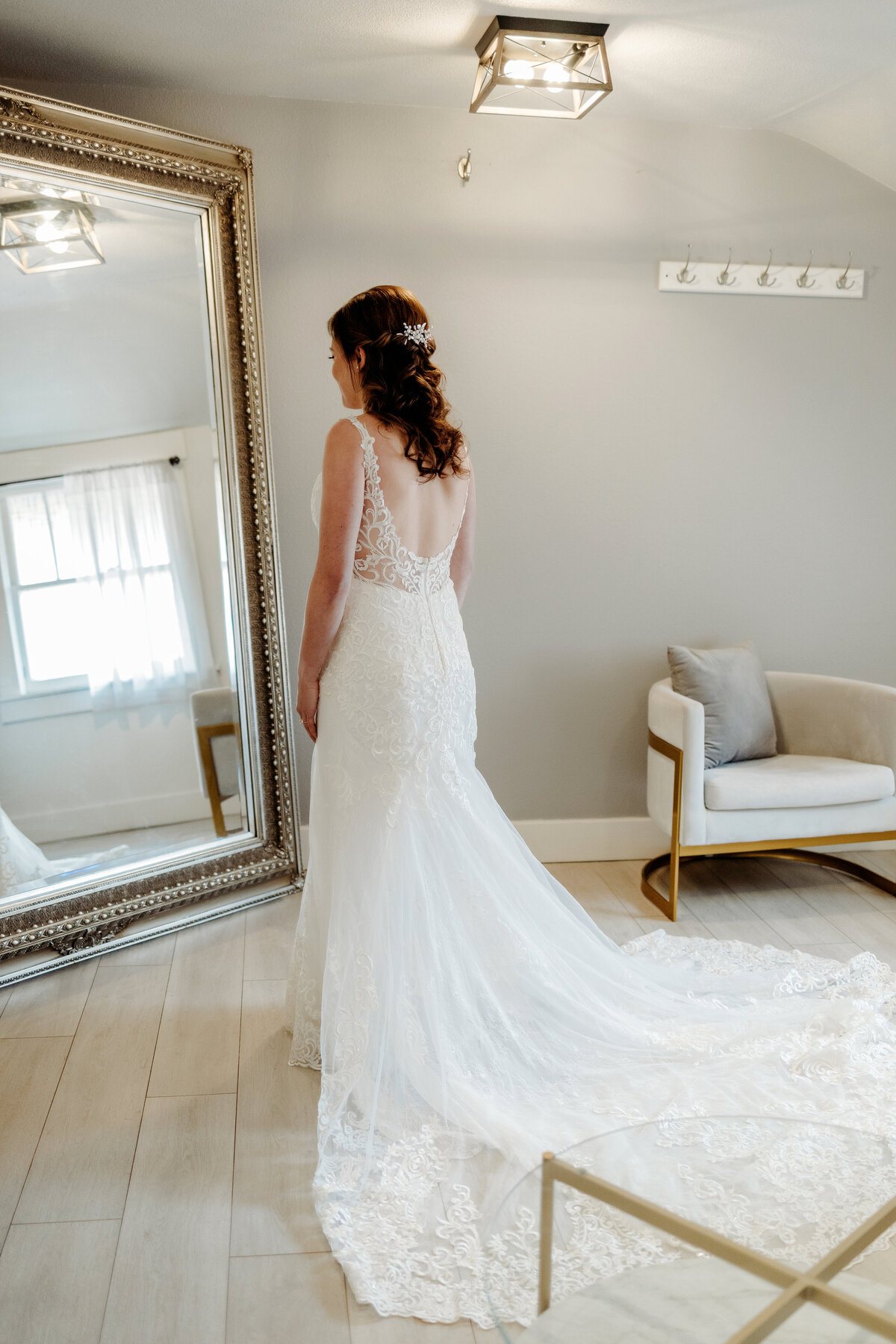Bride looking in large mirror of herself putting her wedding dress on at a Denver wedding venue