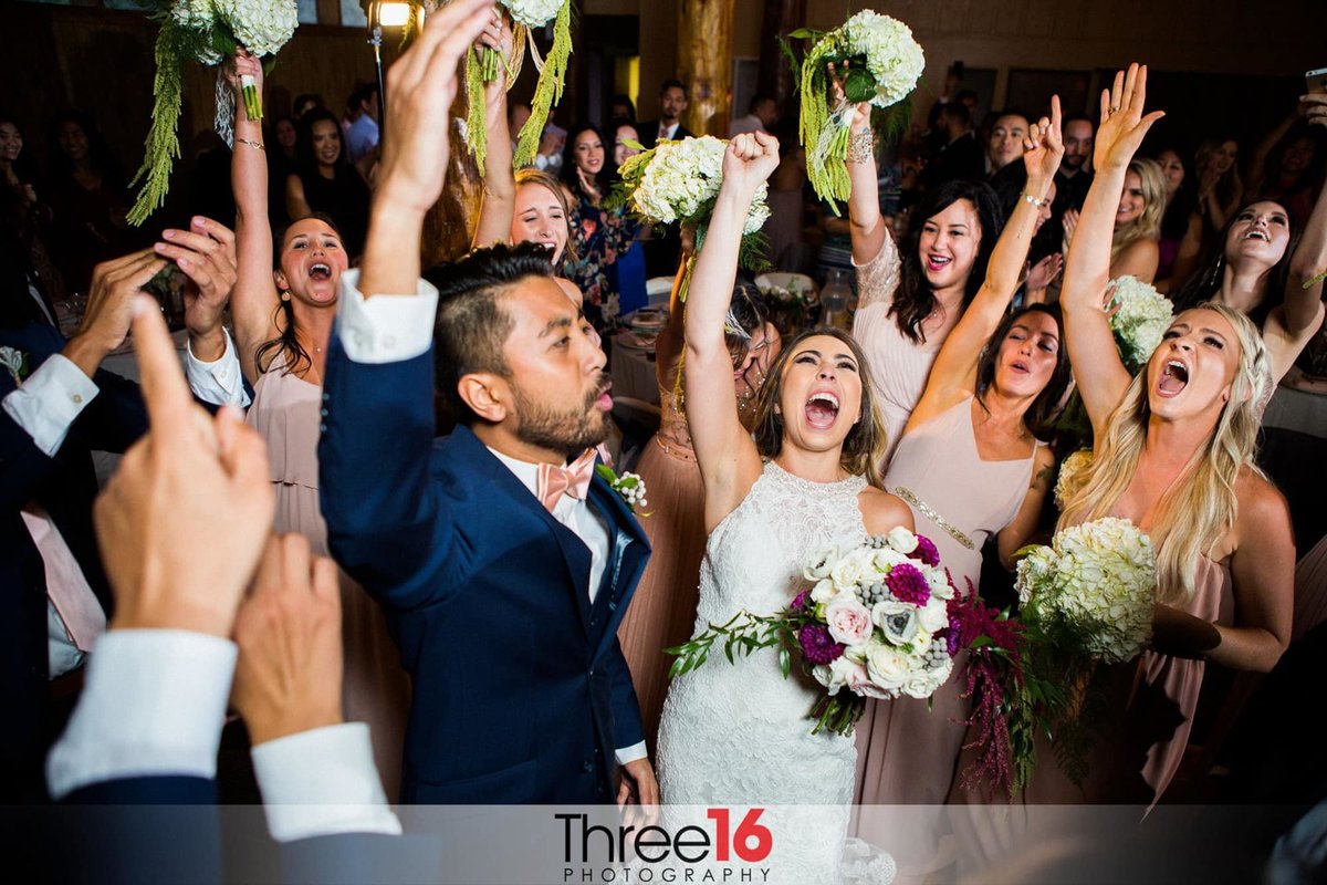 Bride and Groom cheering on the dance floor with their wedding party