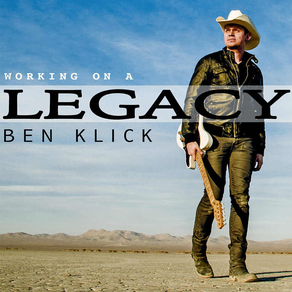 Single Cover Country Artist Ben Klick Title Working On A Legacy Singer walking while holding guitar in desert wearing white cowboy hat