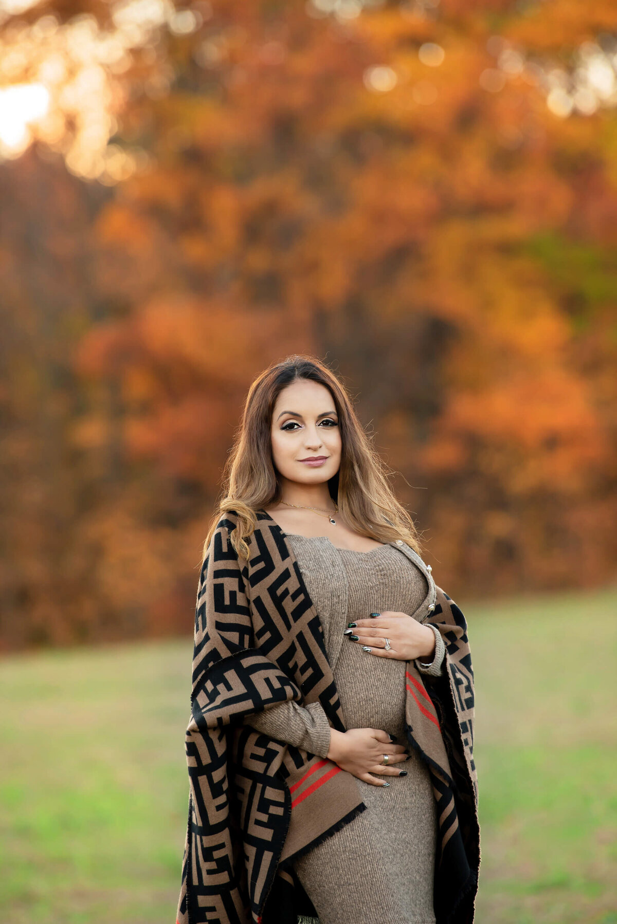 pregnant woman wearing a beige dress for her fall maternity photos in Burlington, ON