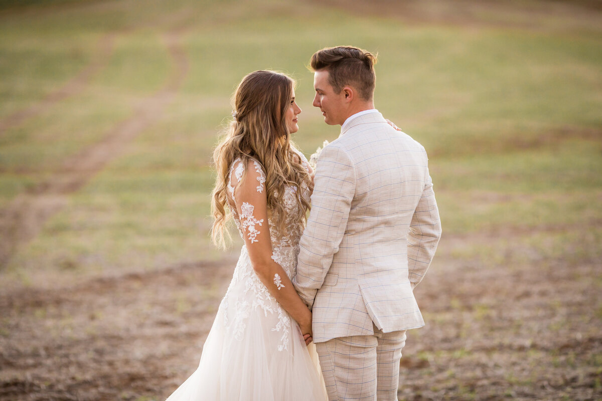 Bride and groom in open field at sunset.