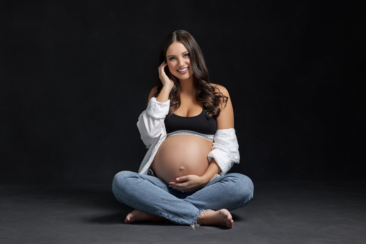 A pregnant woman sitting on the floor with her legs crossed