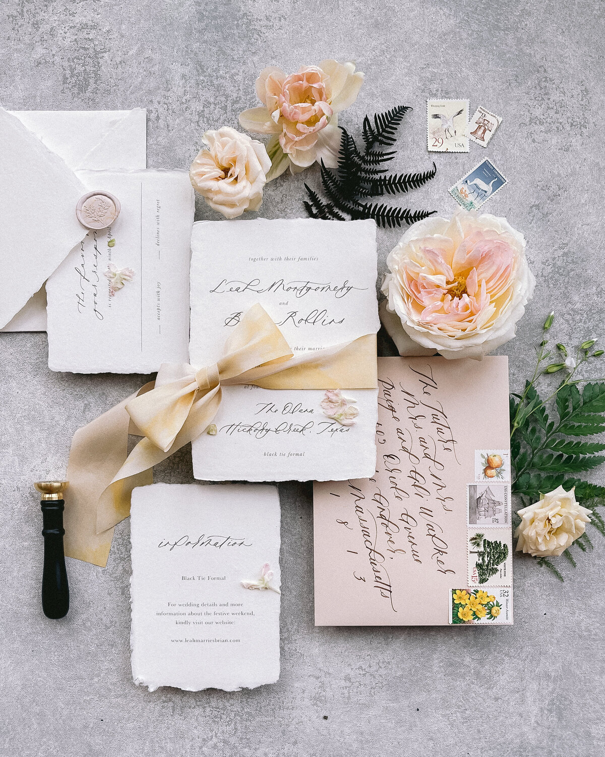 Handmade paper wedding invitation suite styled with romantic florals and handwritten calligraphy.
