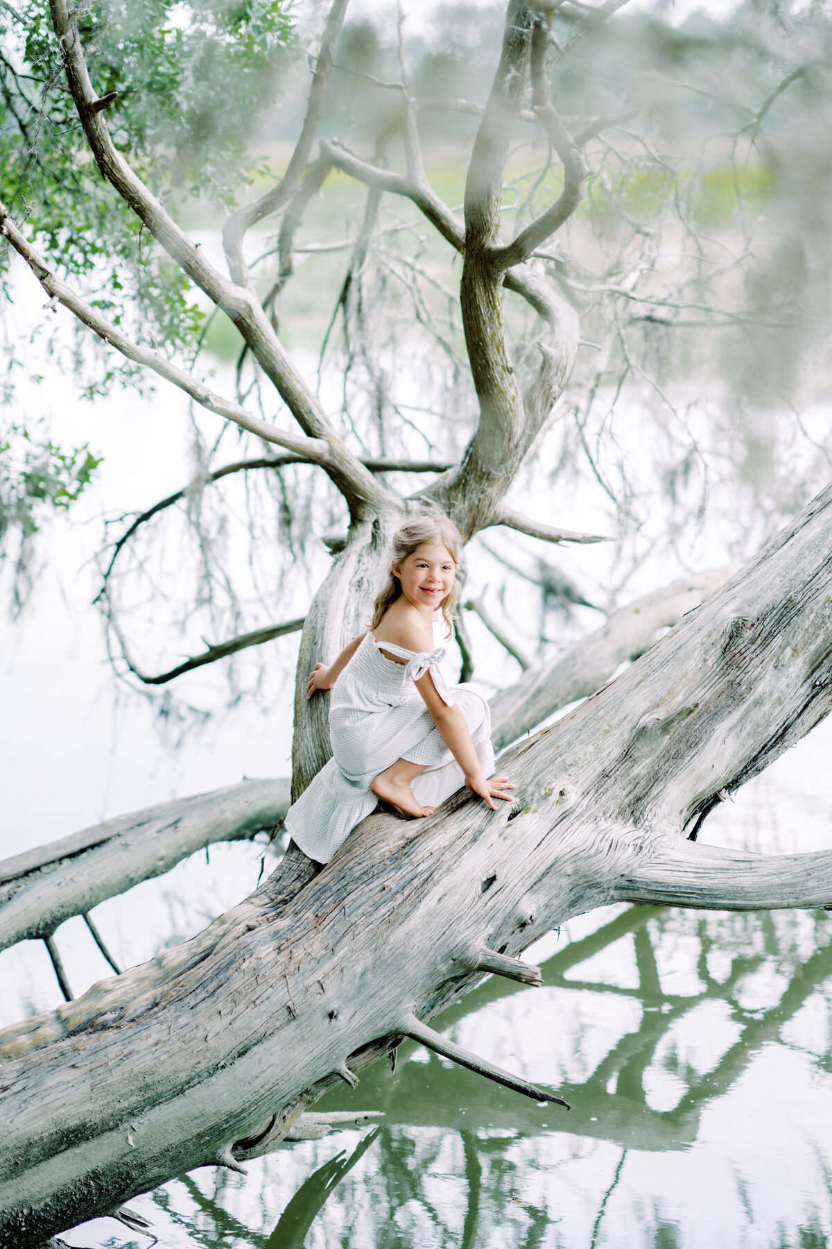 Young girl playing on driftwood at the beach by Savannah family photographer Courtney Cronin