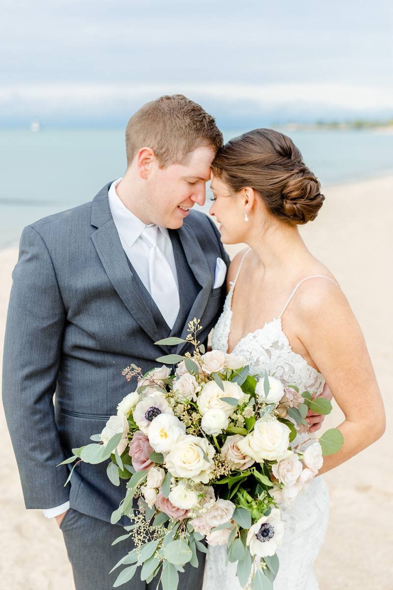 bride and groom smile at one another with park place design bridal bouquet