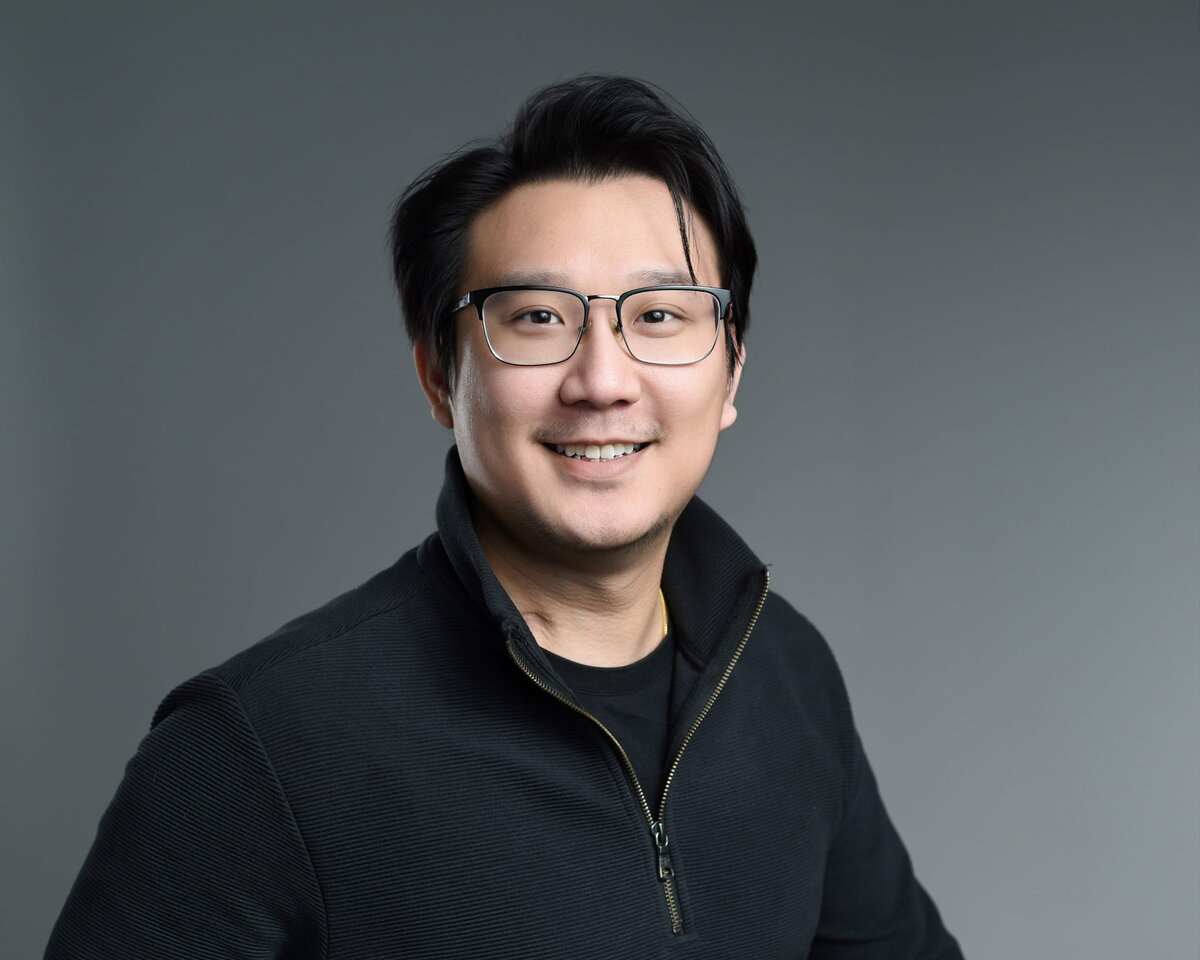 Executive male in dark sweater with confident smile, captured by a Toronto headshot photographer in studio lighting.
