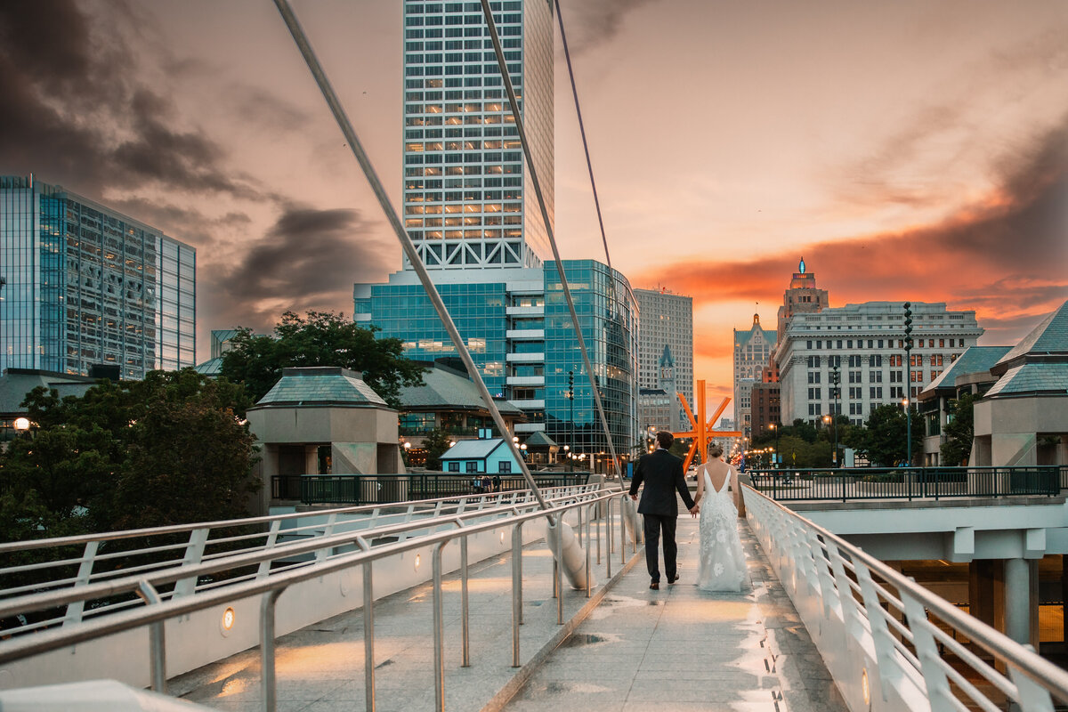 Newlyweds walk in downtown Milwaukee at sunset holding hands