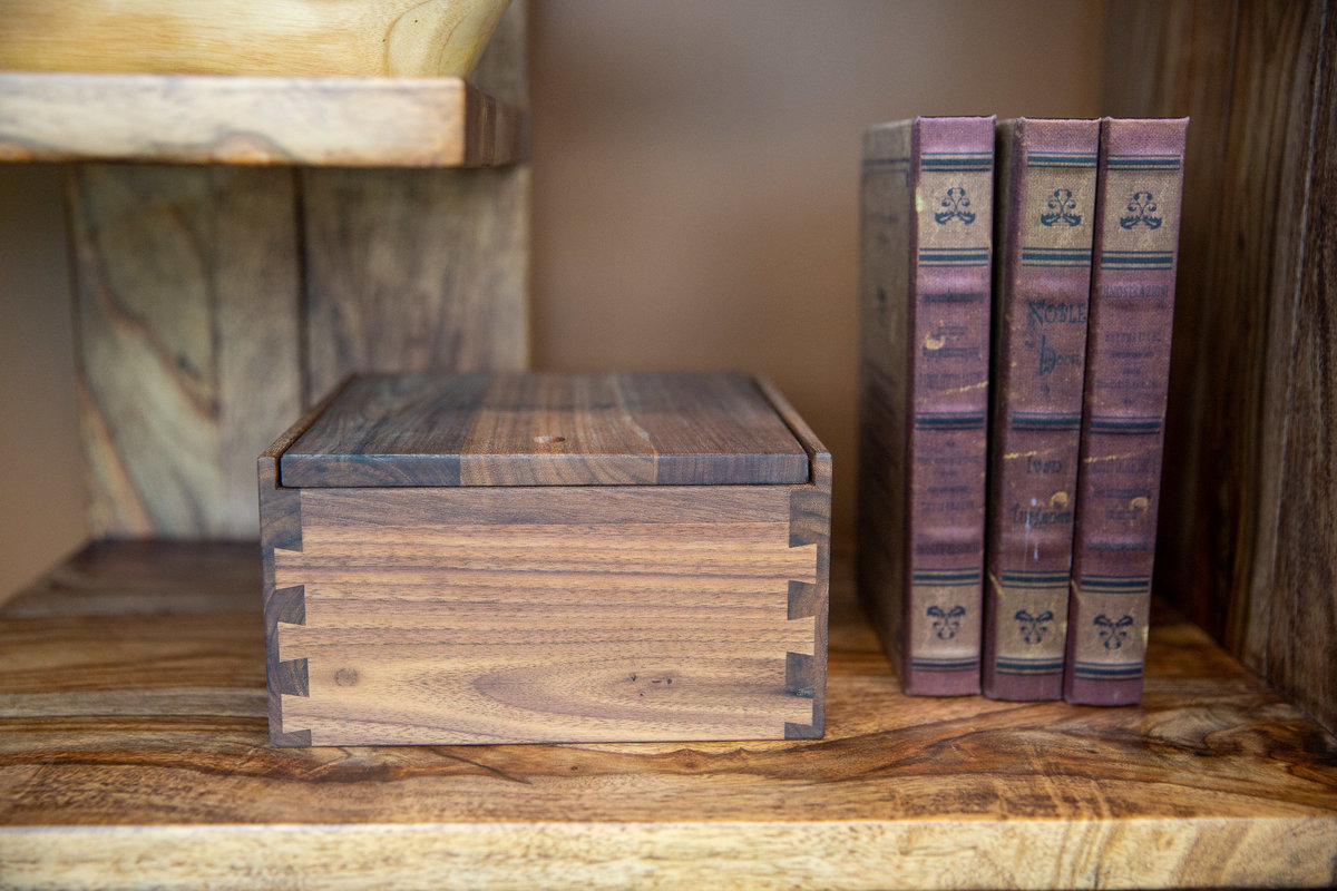 Wooden keepsake wedding box on a shelf next old books.
