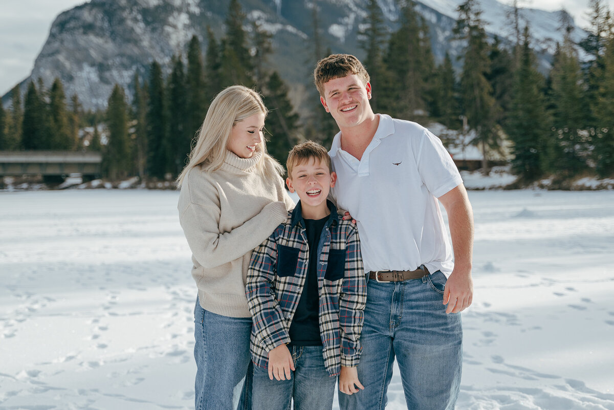 Candid family portrait with young child standing on frozen Bow River in Banff.