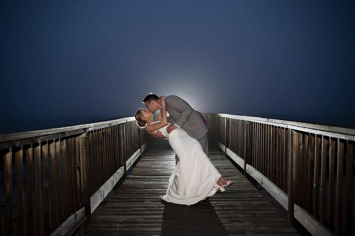 A person dipping their partner and kissing them on a dock 