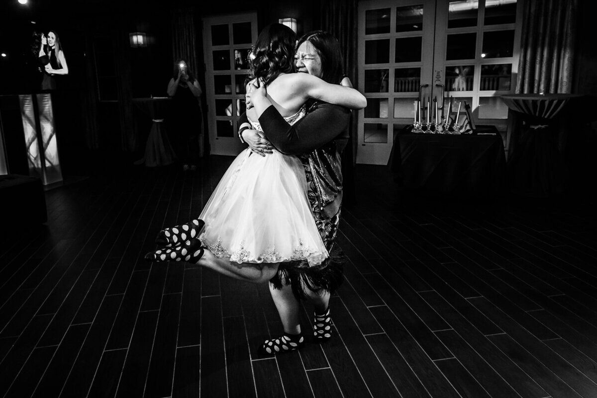 A girl in a dress embraces a woman who lifts her off the floor