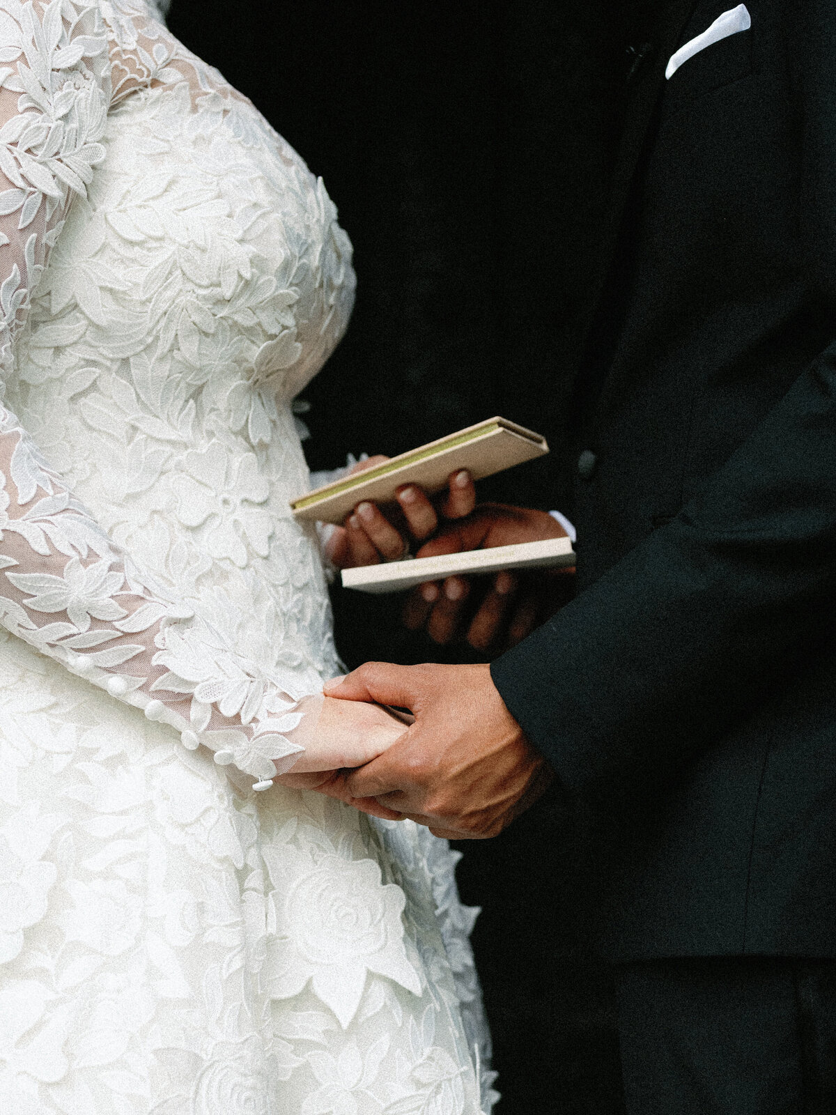 Close-up of bride and groom holding hands and exchanging vows during their fall wedding at Castle Ladyhawke.