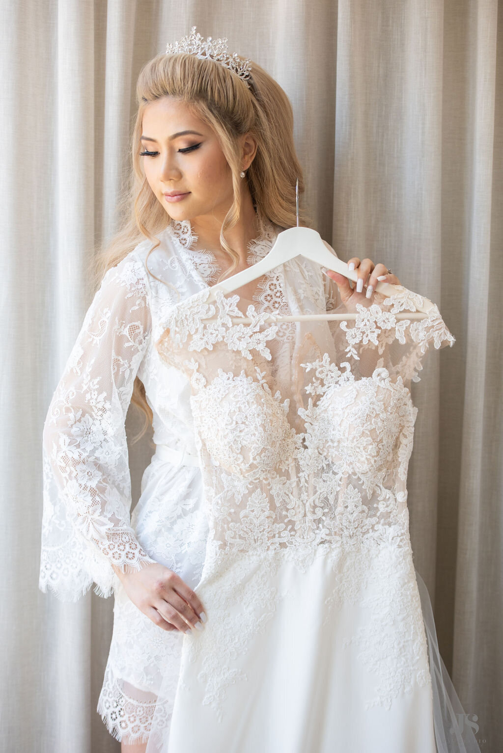 Bride poses with her lace wedding dress in a robe with a crown at the Halcyon Hotel in Cherry Creek, Colorado.