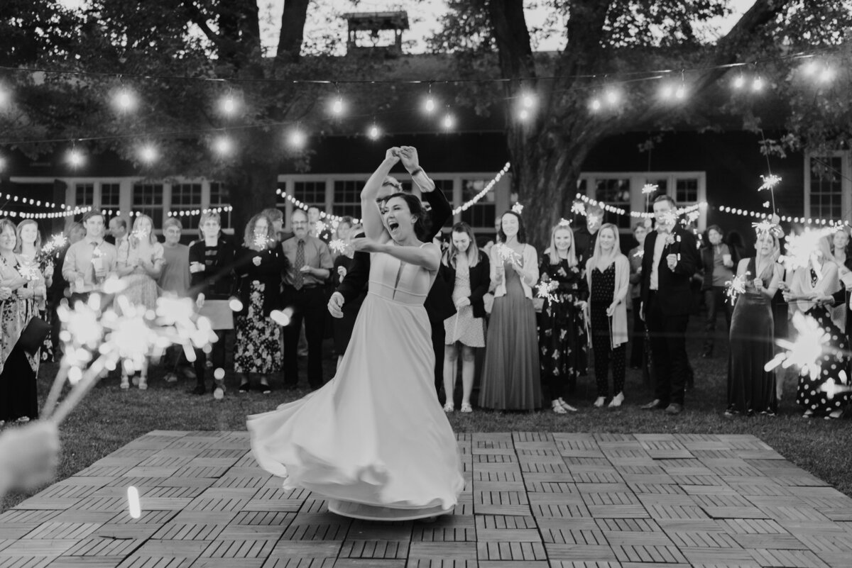 couple dances outside under bistro light surrounded by sparklers