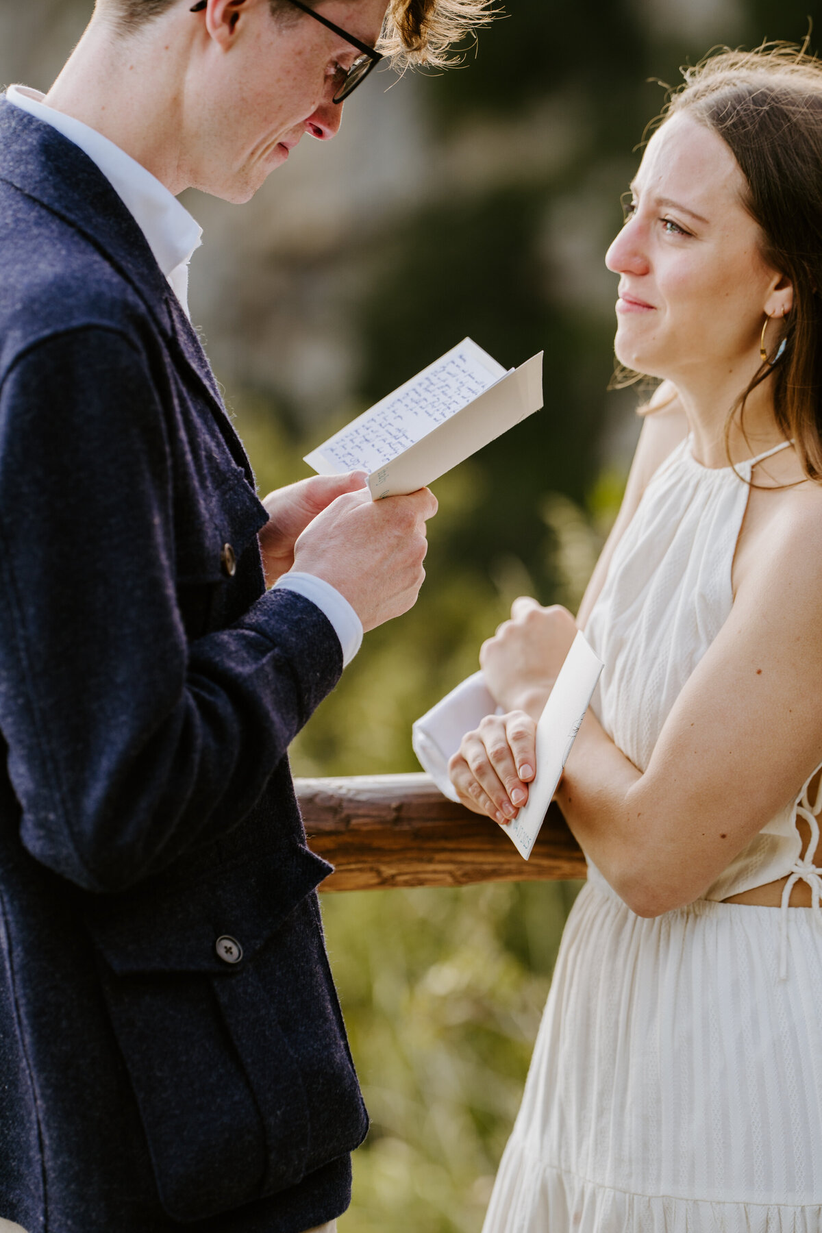 Couple reading vows at wooden railing.