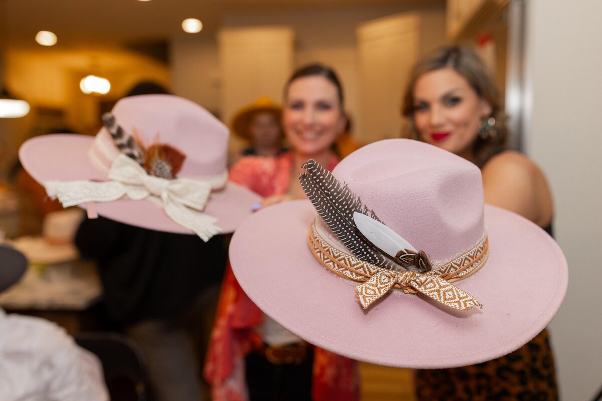 two women holding up hats for the camera