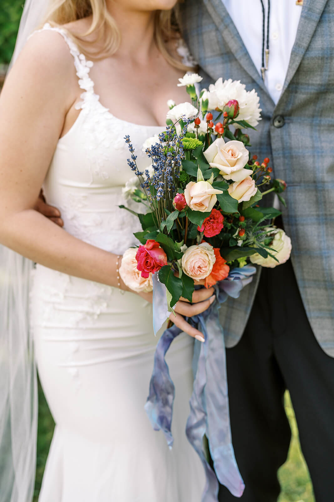 A close up of bride and groom holding a bouquet of flowers.