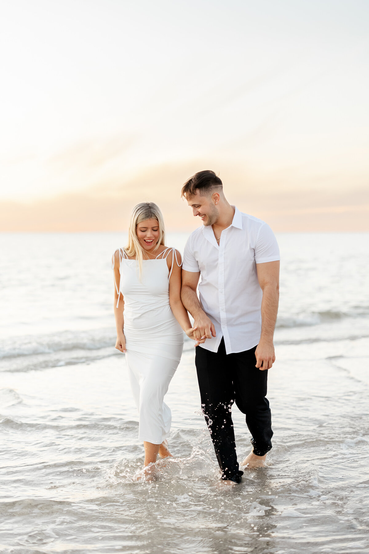 couple holding hands and walking in the ocean by wedding photographer in fort lauderdale