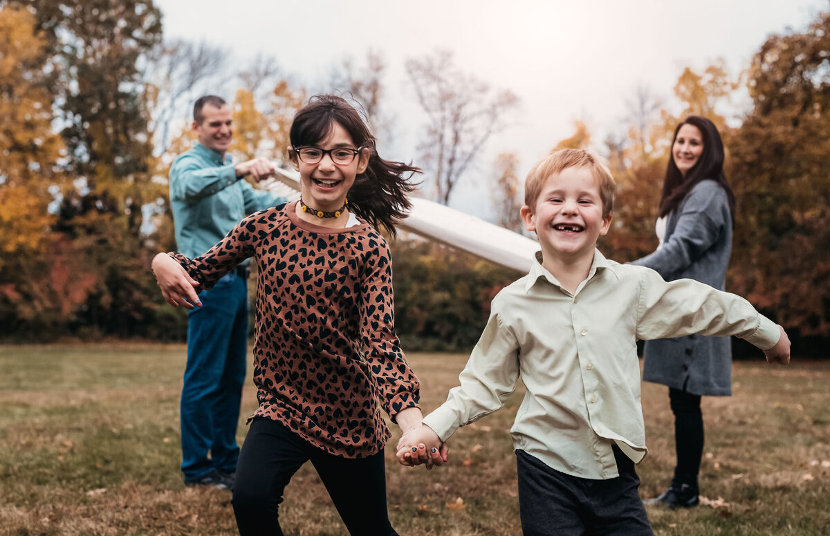 Family photo of kids smiling and running while holding hands at stark park in manchester nh by lisa smith photography