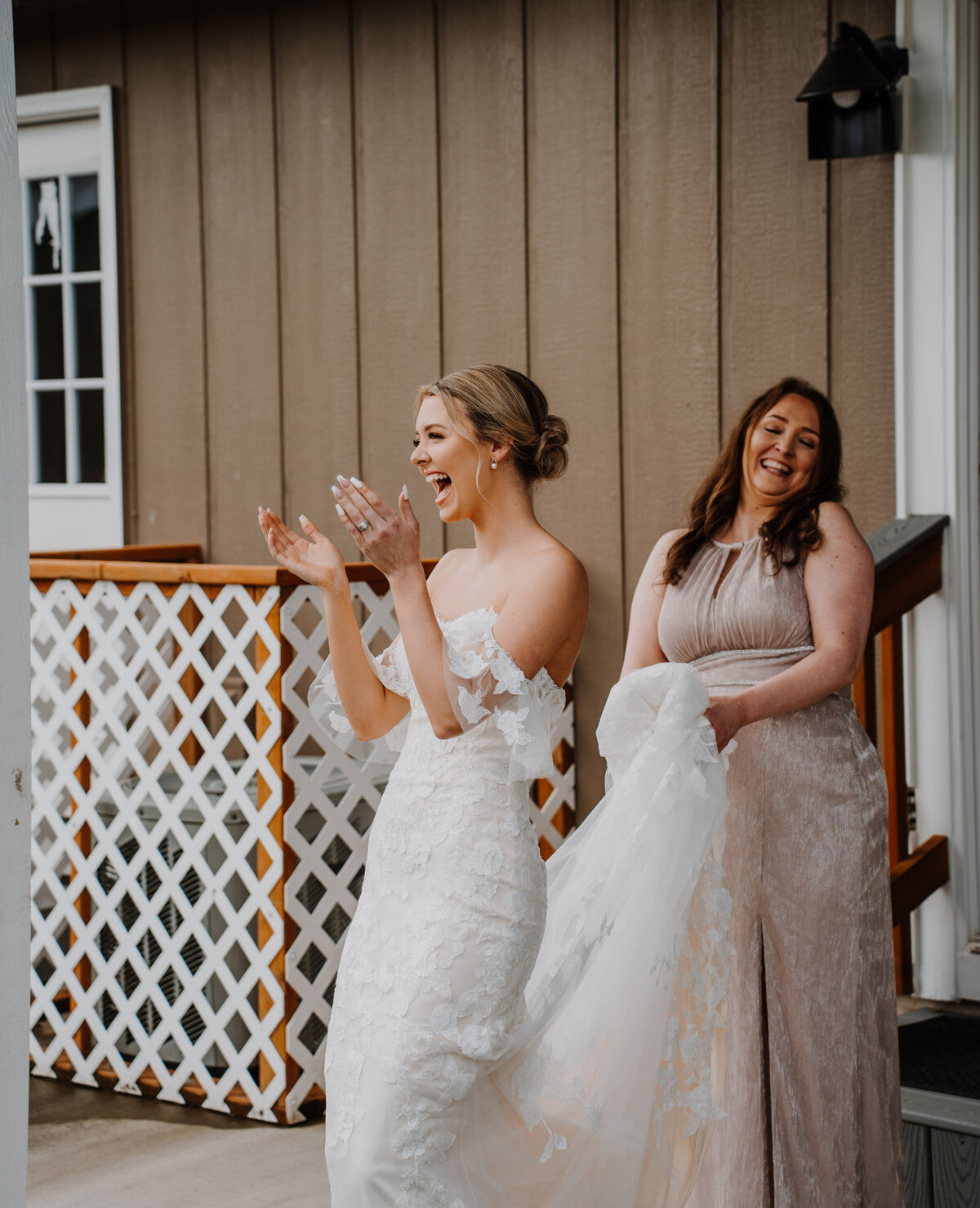Bride smiling while mother holds her dress train